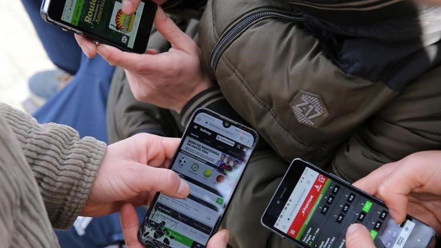 Un grupo de jóvenes juegan con sus móviles en paginas de apuestas deportivas online.
