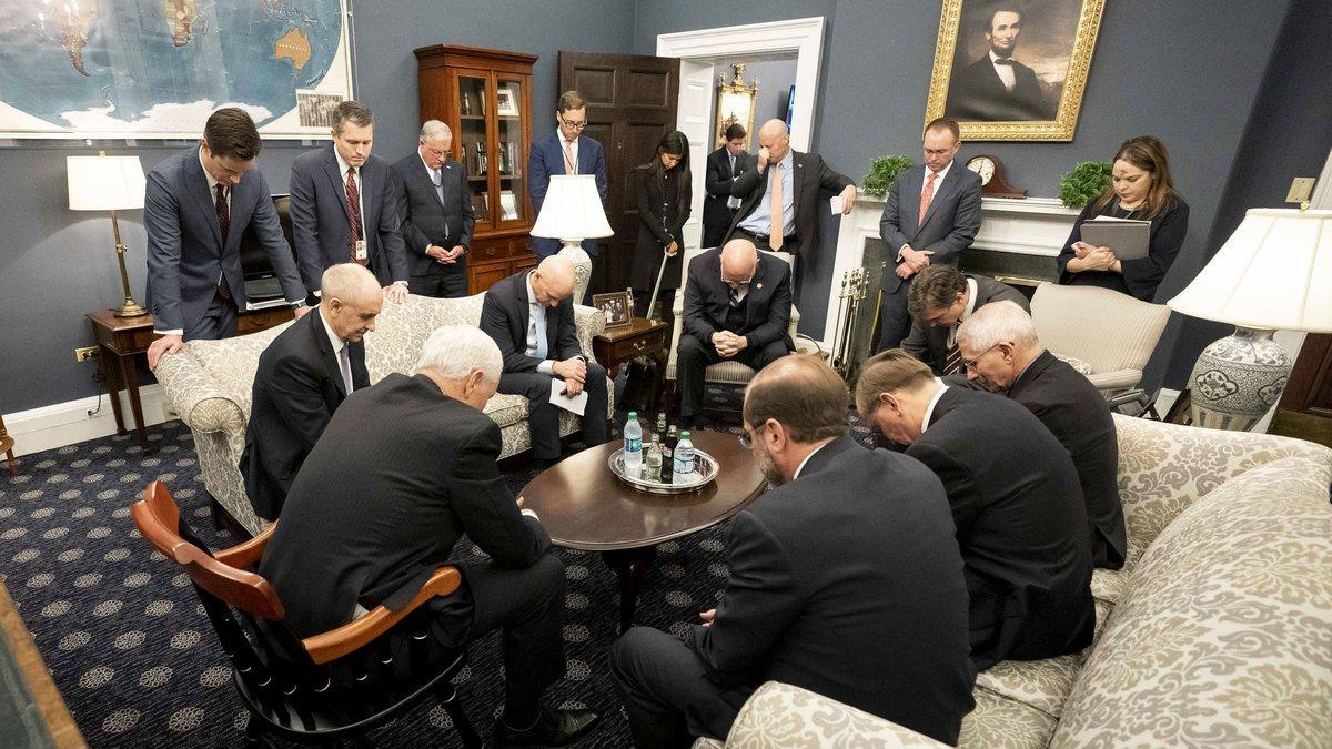 Mike Pence (sentado en una silla en primer plano, de espaldas) reza junto a su equipo de trabajo en la Casa Blanca, el 26 de febrero del 2020