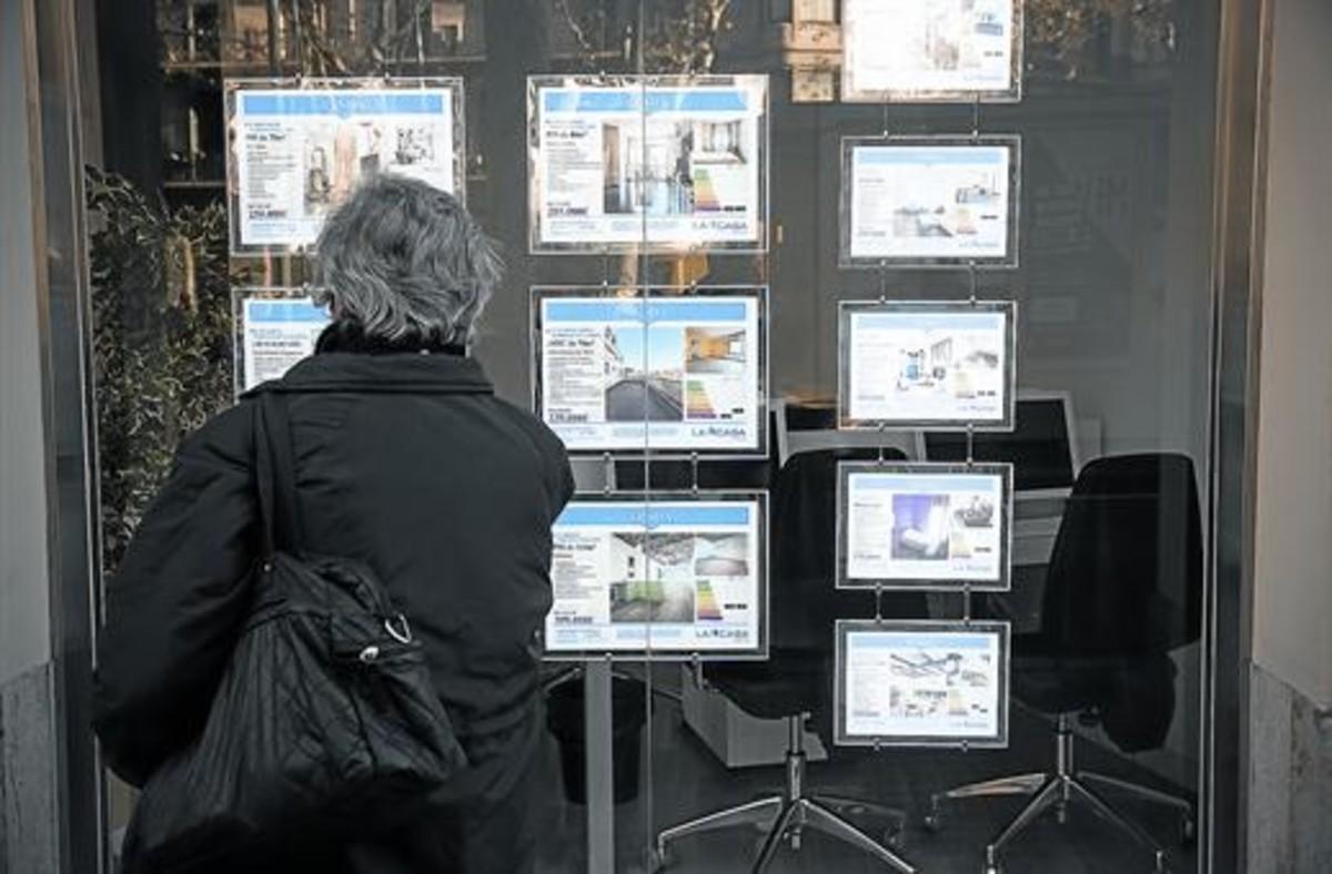 Una mujer consulta anuncios de pisos en una inmobiliaria de Barcelona. Una mujer consulta anuncios de pisos en una inmobiliaria de Barcelona.