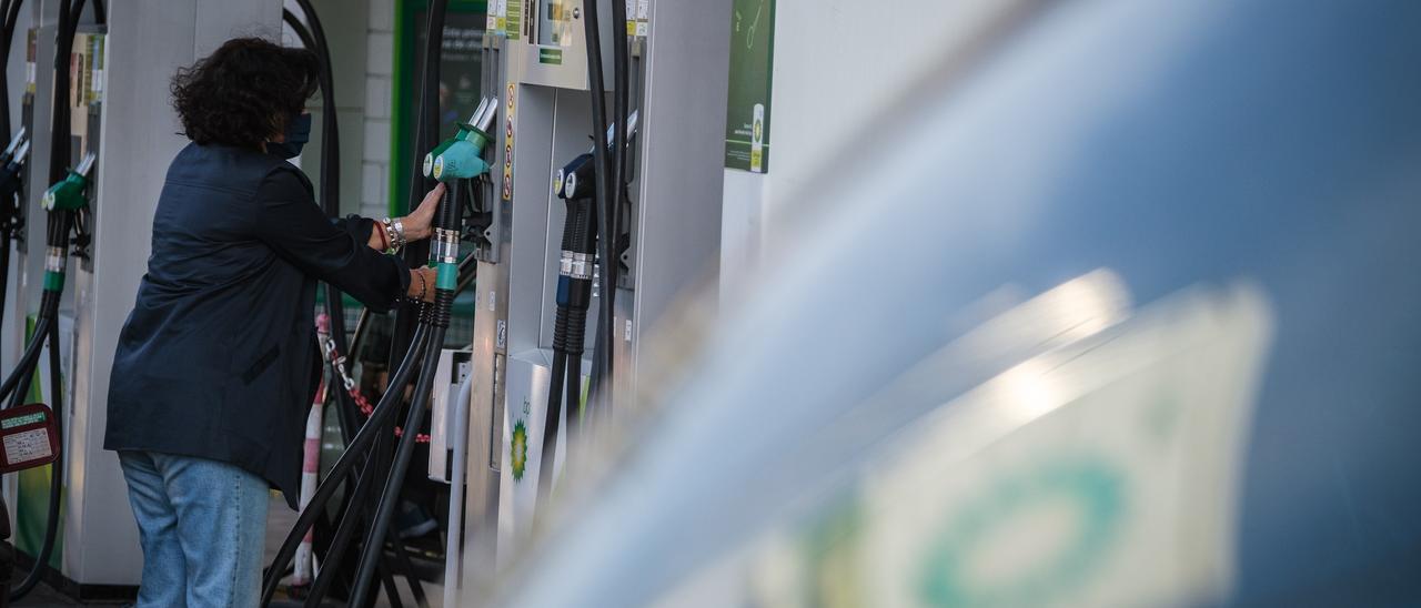 Una mujer junto a un surtidor en una gasolinera.