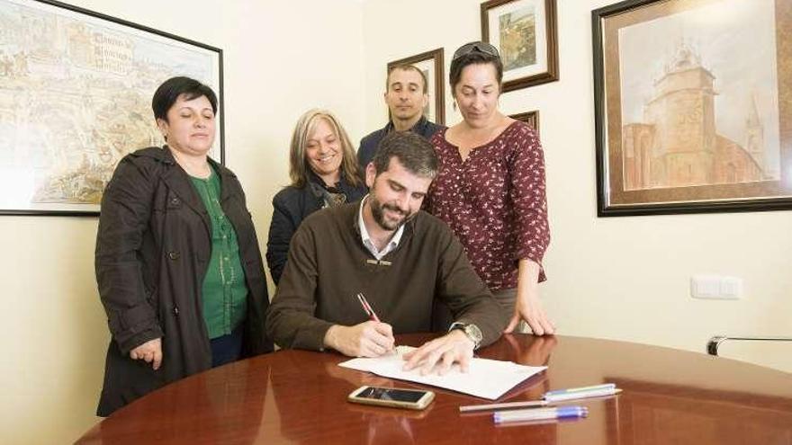 Martín Seco, en el centro, firma los compromisos ante notario.