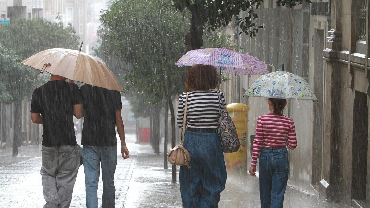 Los ourensanos se refugian con paraguas de la lluvia.