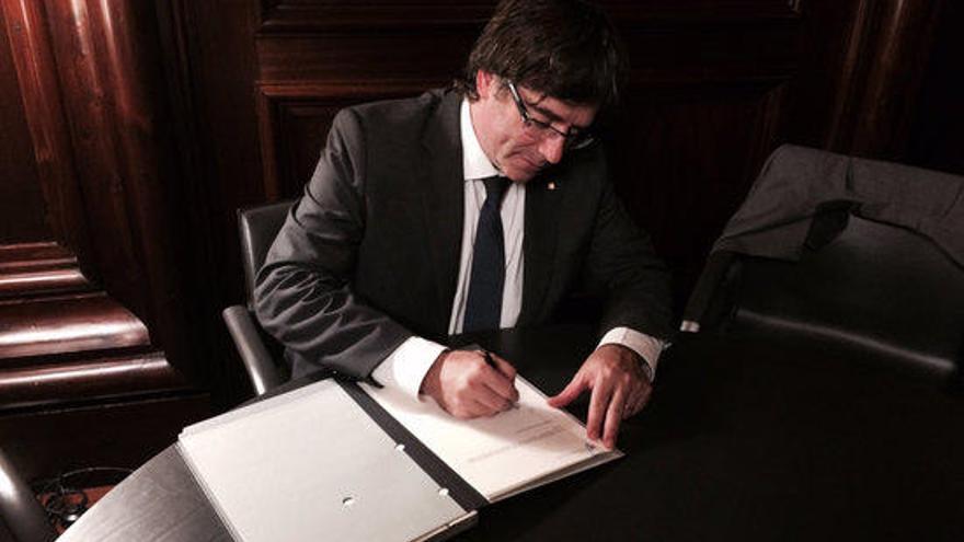 El president Carles Puigdemont signa i promulga la llei del referèndum.