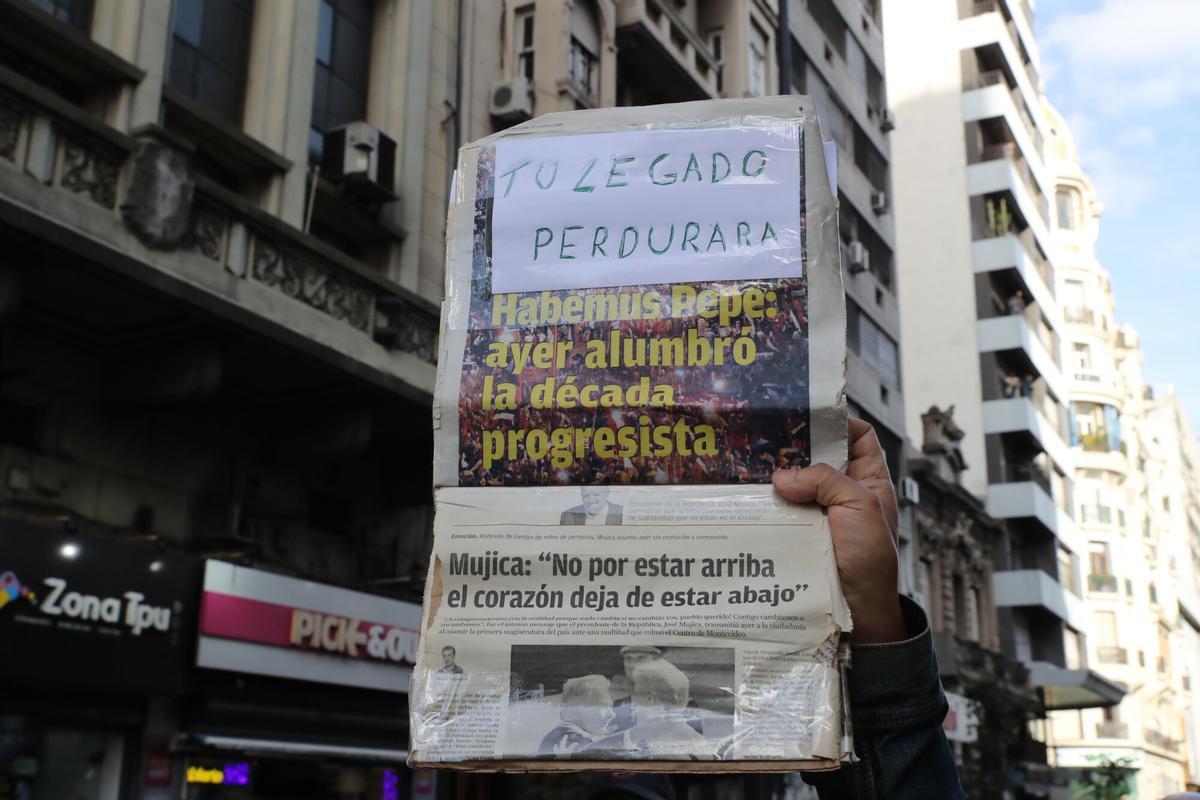 AME7458. MONTEVIDEO (URUGUAY), 14/05/2025.- Una persona sostiene un cartel durante el cortejo fúnebre del expresidente José Mujica este miércoles, en Montevideo (Uruguay). El cortejo fúnebre de Mujica partió desde el Palacio Estevez de Montevideo, donde el actual mandatario, Yamandú Orsi, colocó el pabellón patrio sobre el féretro. EFE/ Raúl Martínez