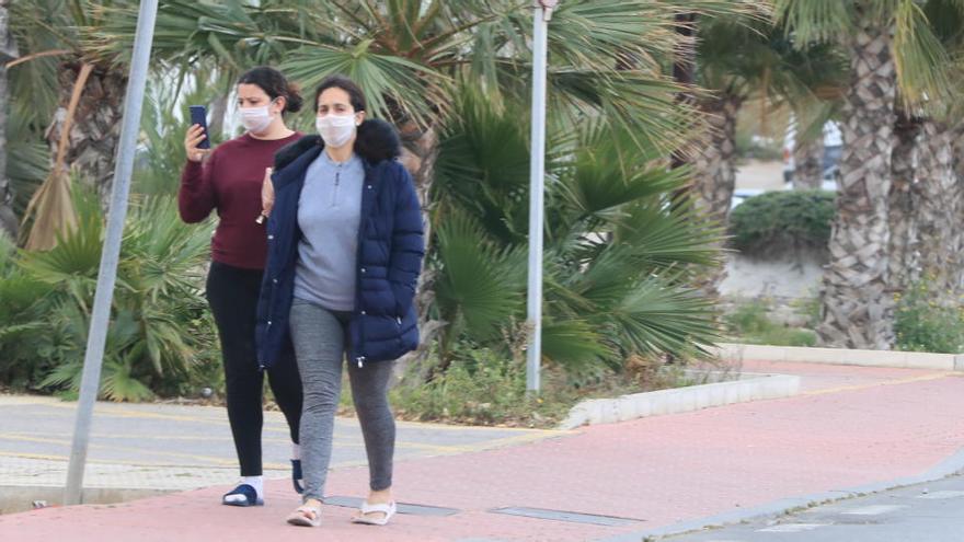 Dos personas con mascarillas caminan por la calle.