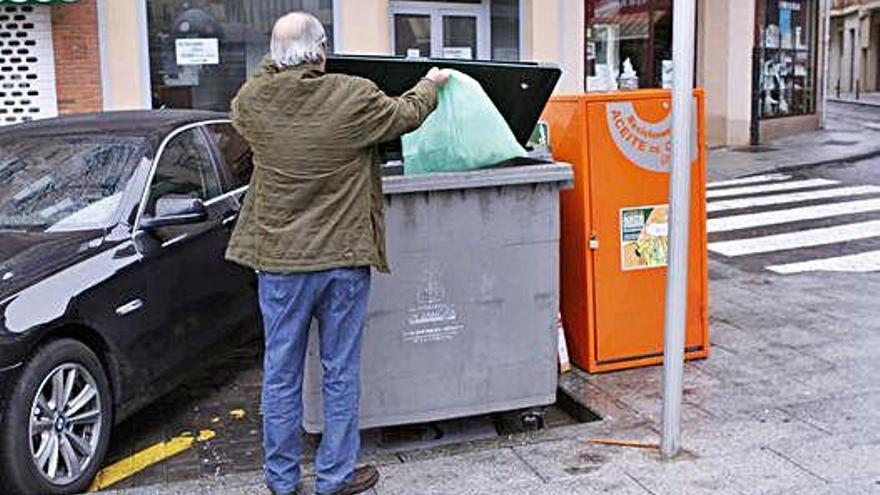 Un hombre tira la basura en un contenedor de la ciudad.