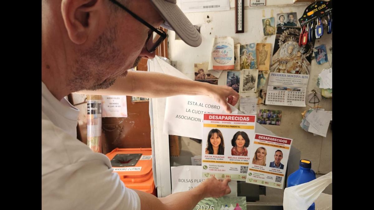 Peter Pogacar, pegando el cartel de la desaparición de su hija y su exmujer en una tienda de Gran Canaria.