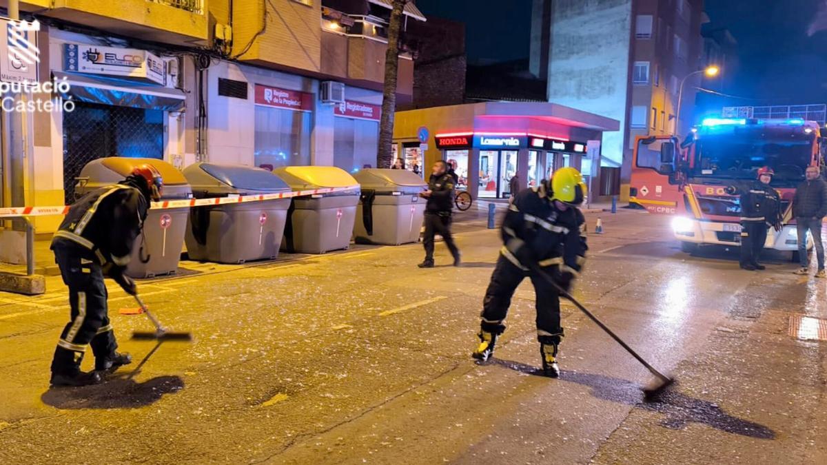 Los bomberos, retirando los cristales que han caído a la calle tras la deflagración en Benicarló.
