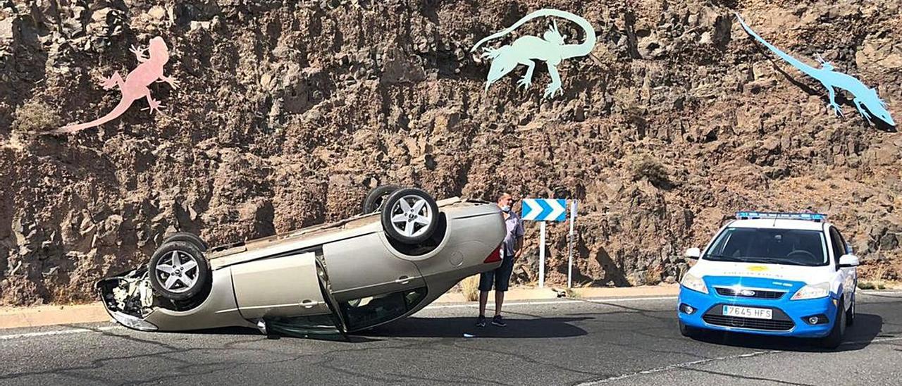 El coche volcado en la GC-100, junto a la Policía Local, en la curva conocida como la de los lagartos, en  Agüimes, ayer. | | LP / DLP