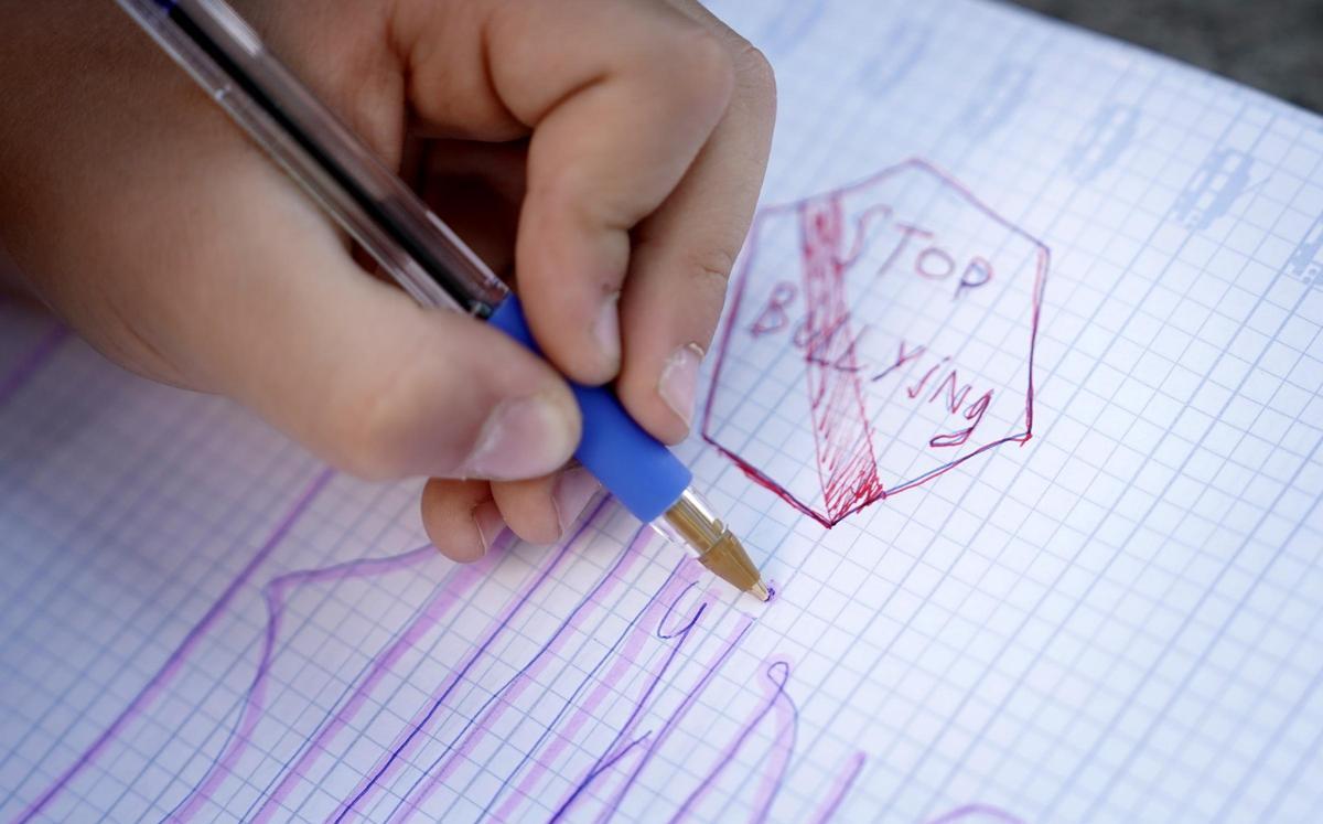 Un niño de primaria escribe un cartel contra el acoso escolar, en un colegio de Madrid.
