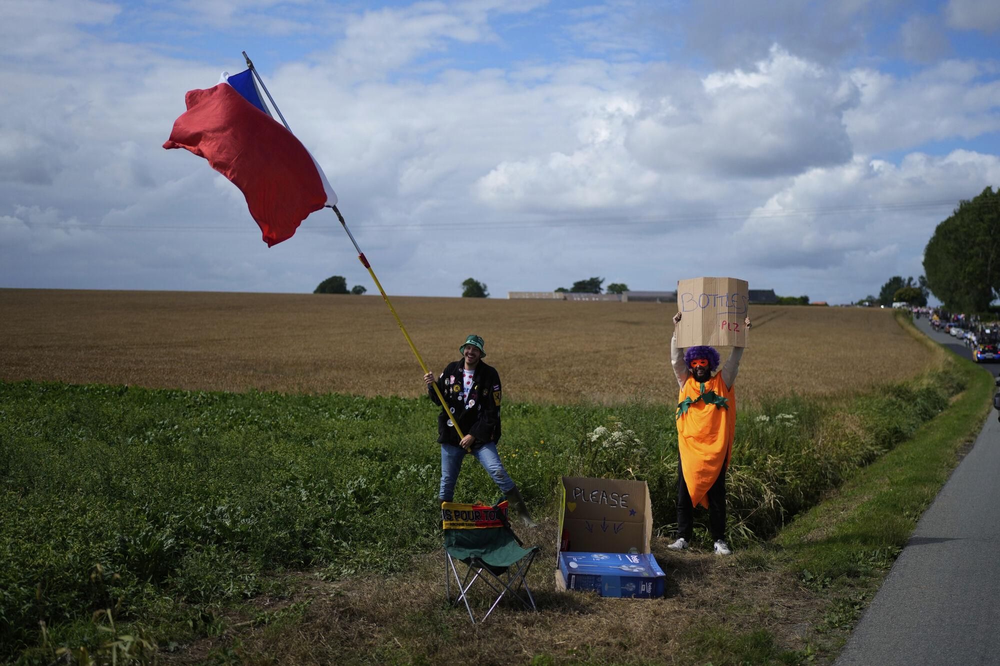 Fans ask for bottles during the third stage of the Tour de France cycling race over 178.3 kilometers (110.8 miles) with start in Valenciennes and finish in Dunkerque, France, Monday, July 7, 2025. (AP Photo/Mosa'ab Elshamy)