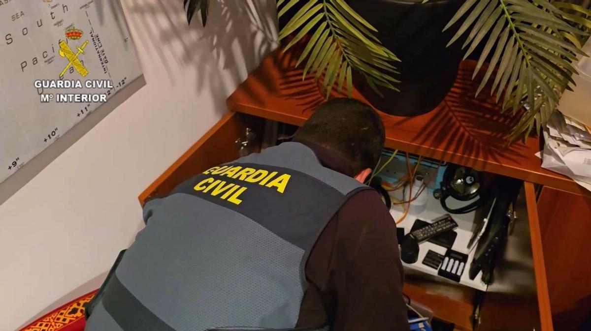 Un guardia examina el material informático hallado en el domicilio.