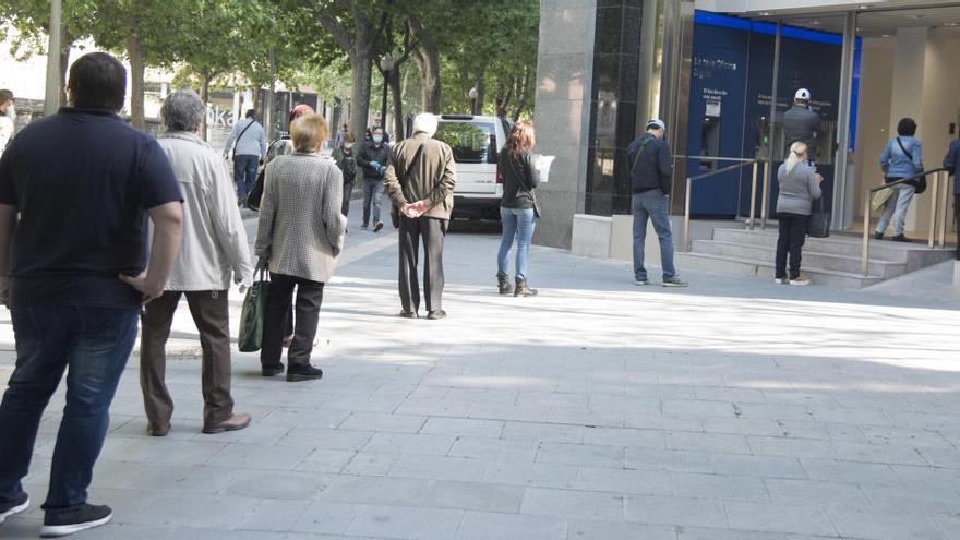 Persones fent cua a la porta d&#039;un banc, a Manresa |