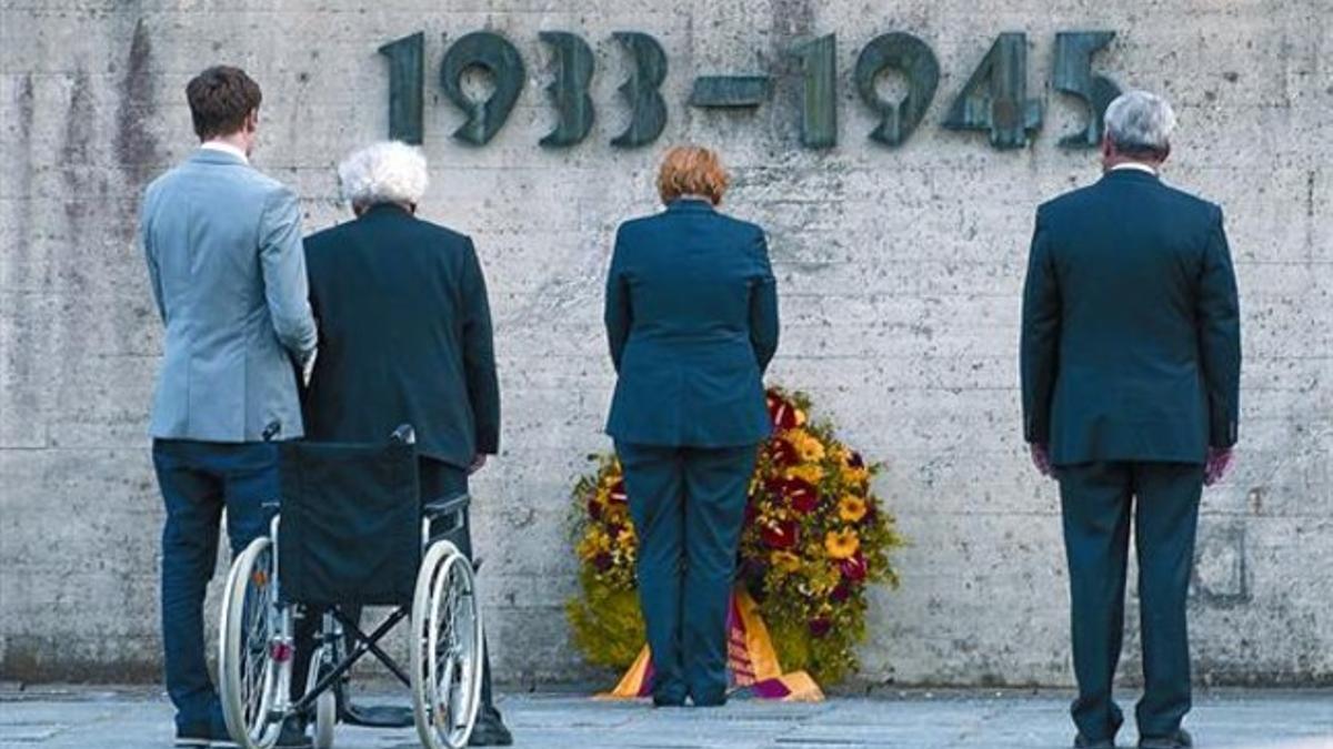 Ofrenda 8 Merkel deposita una corona de flores en Dachau, junto al ministro de Cultura bávaro (derecha) y un superviviente del Holocausto, ayer.