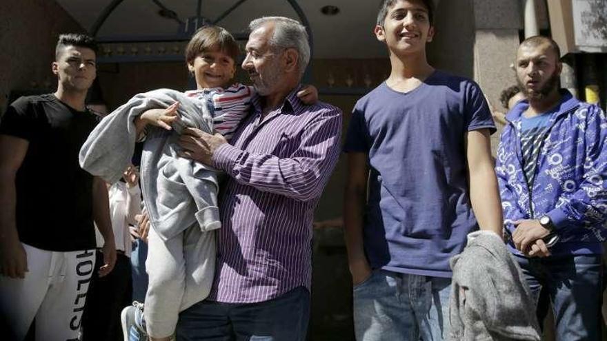 Mohsen y dos hijos, ante el portal de su nueva casa en Getafe.  // Reuters