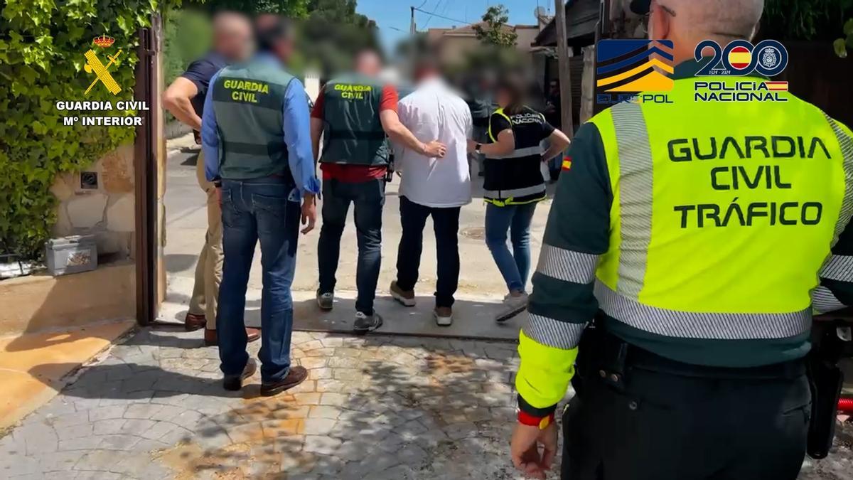 Agentes de la Guardia Civil y de la Policía Nacional conducen a uno de los detenidos en la macrooperación contra el tráfico de coches.