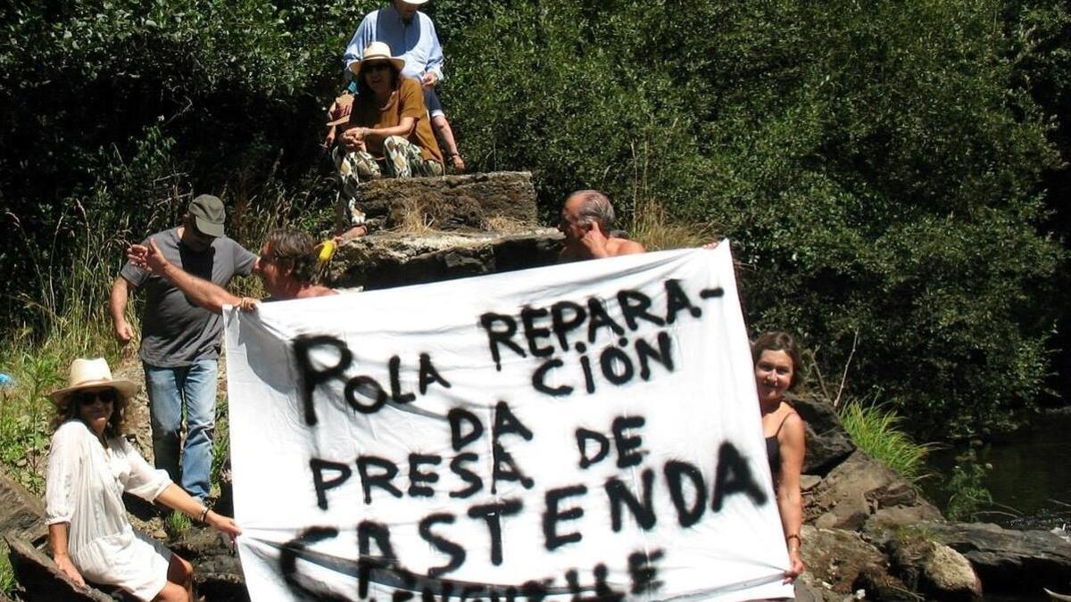 Vecinos del entorno de Tordoia con un cartel reivindicativo para reparar la presa de Castenda