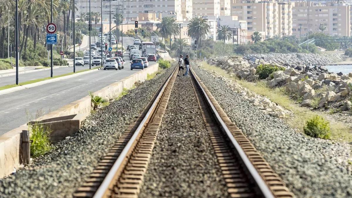 Dos personas cruzan las vías del tren en la fachada litoral de Alicante.