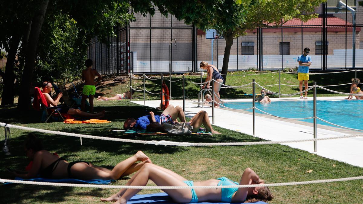 Personas tomando el sol en la piscina de Pinilla.