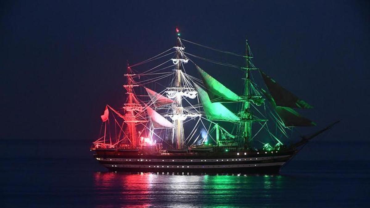 Imagen nocturna del 'Amerigo Vespucci' iluminado con la bandera de Italia.