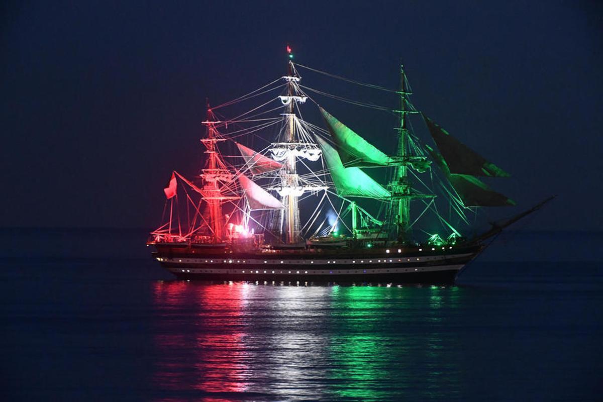 Imagen nocturna del 'Amerigo Vespucci' iluminado con la bandera de Italia.