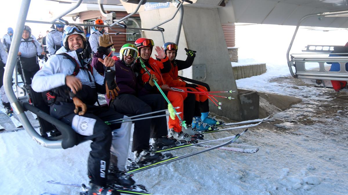 Quatre esquiadors saluden just després de pujar al telecadira el dia de l'obertura de l'estació de Baqueira Beret