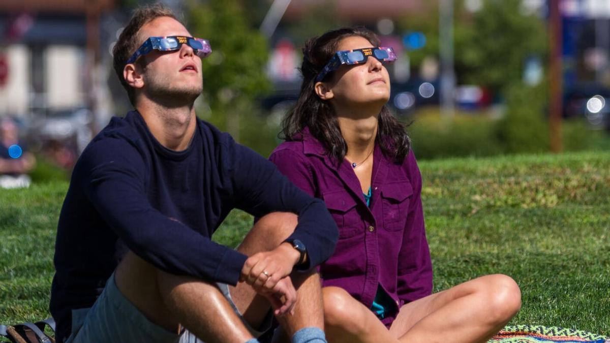 Dos personas con gafas especiales para ver eclipses.