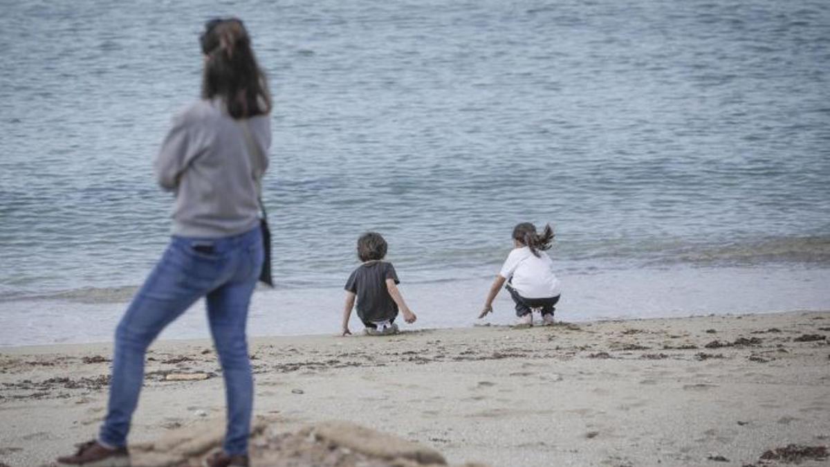 Una madre con sus dos hijos en la playa.