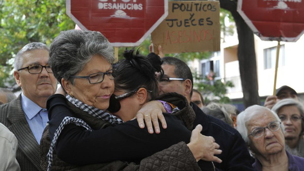 La hermana de José Miguel Domingo (izquierda), el comerciante que se quitó la vida el pasado jueves horas antes de ser desahuciado de su vivienda, abraza a otro familiar durante una concentración para pedir cambios legislativos, el lunes en el barrio