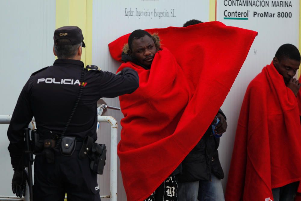 A migrant adjusts a blanket upon arriving on a ...