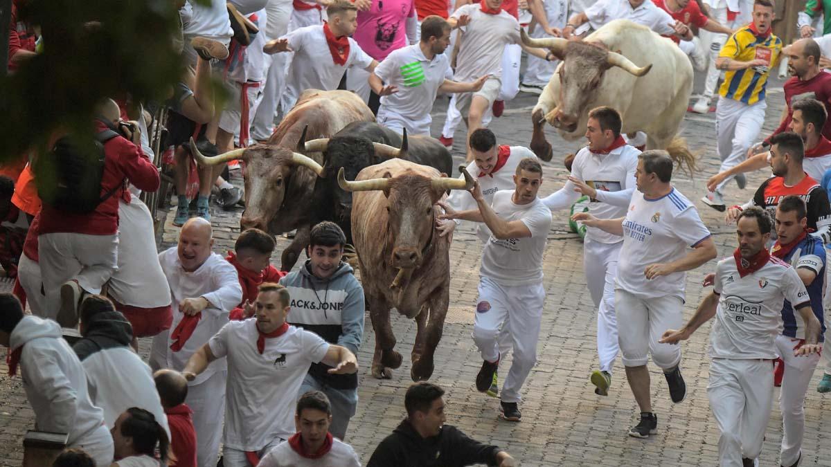 Los participantes corren delante de los toros durante el encierro de las fiestas de San Fermín en Pamplona.