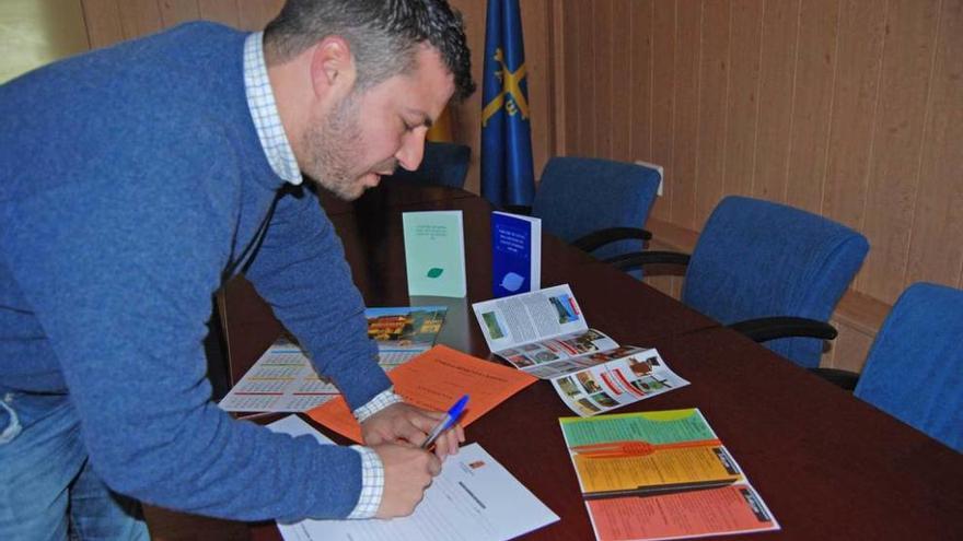Aitor García firma un documento en asturiano.