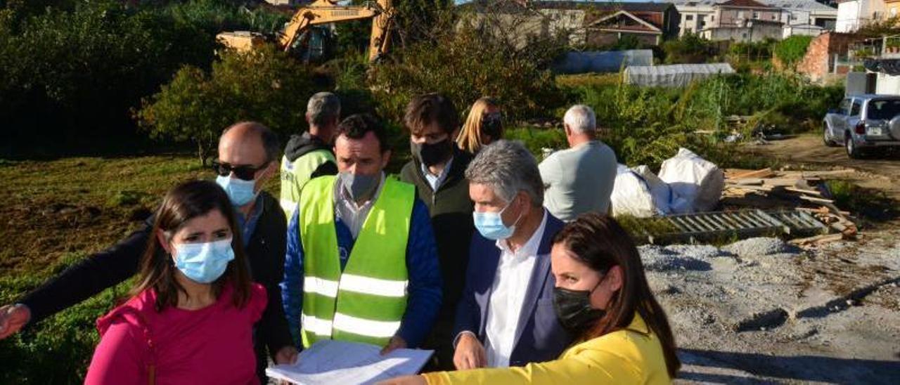 Arriba, responsables de Covsa, el Concello y la Diputación, ayer, en los terrenos, con planos de la obra y la maquinaria al fondo. Abajo, plano de los terrenos, con el espacio para el centro de salud en rosa.   | // G.N.