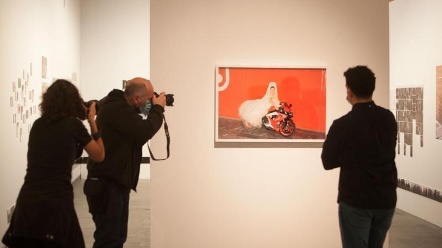 Carlos Aguilera observa una de sus fotos mientras es fotografiado en la exposición del MuVIM. | FERNANDO BUSTAMANTE