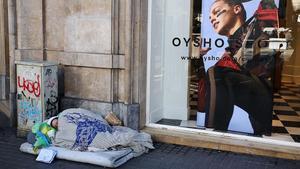 Una persona sin hogar, durmiendo en una calle del centro de Barcelona. 