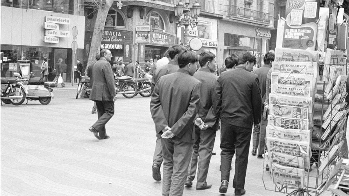 Varios peatones pasan por delante de un kiosco de la Rambla, en 1977.
