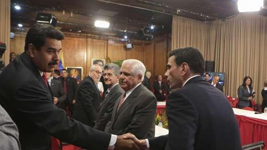 Maduro (izda.) estrecha la mano del líder opositor, Capriles.  // Efe