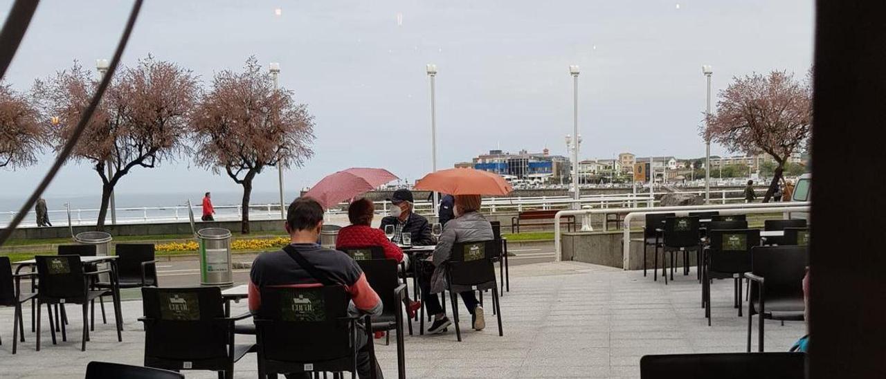 Gente con paraguas en una terraza de Gijón