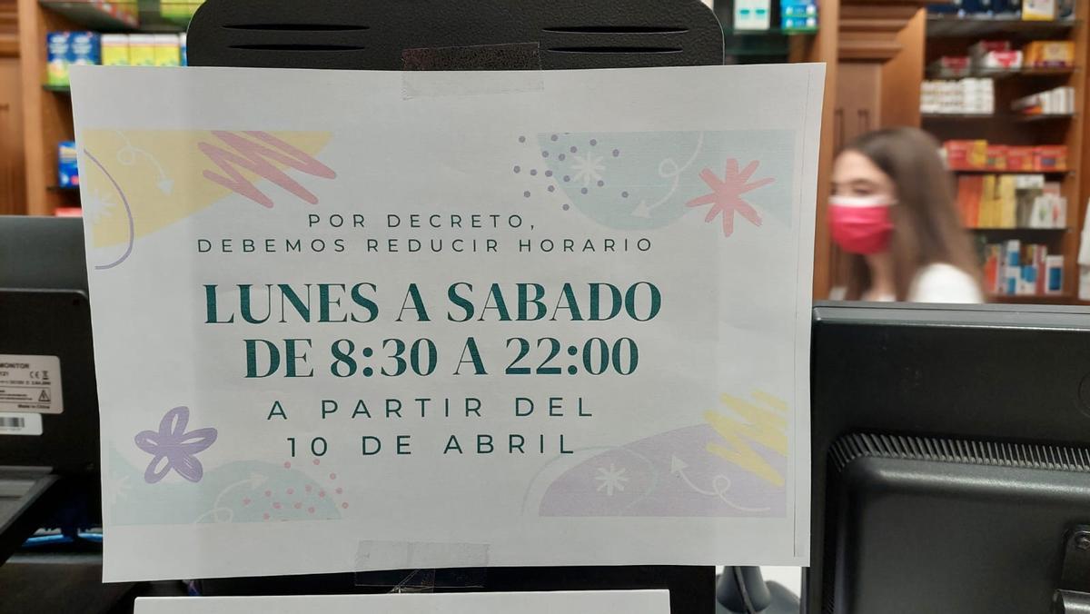 Cartel en una farmacia que anuncia la reducción de su horario.