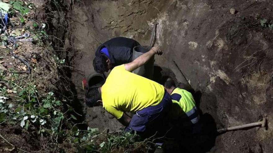 Operarios municipales, en la noche del lunes, ante la tubería en la que se produjo una rotura.