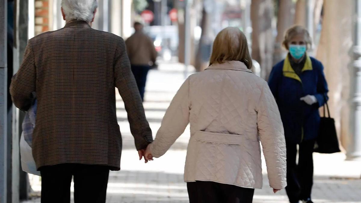 Dos personas mayores pasean de la mano.