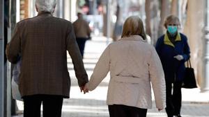 Dos personas mayores pasean de la mano.