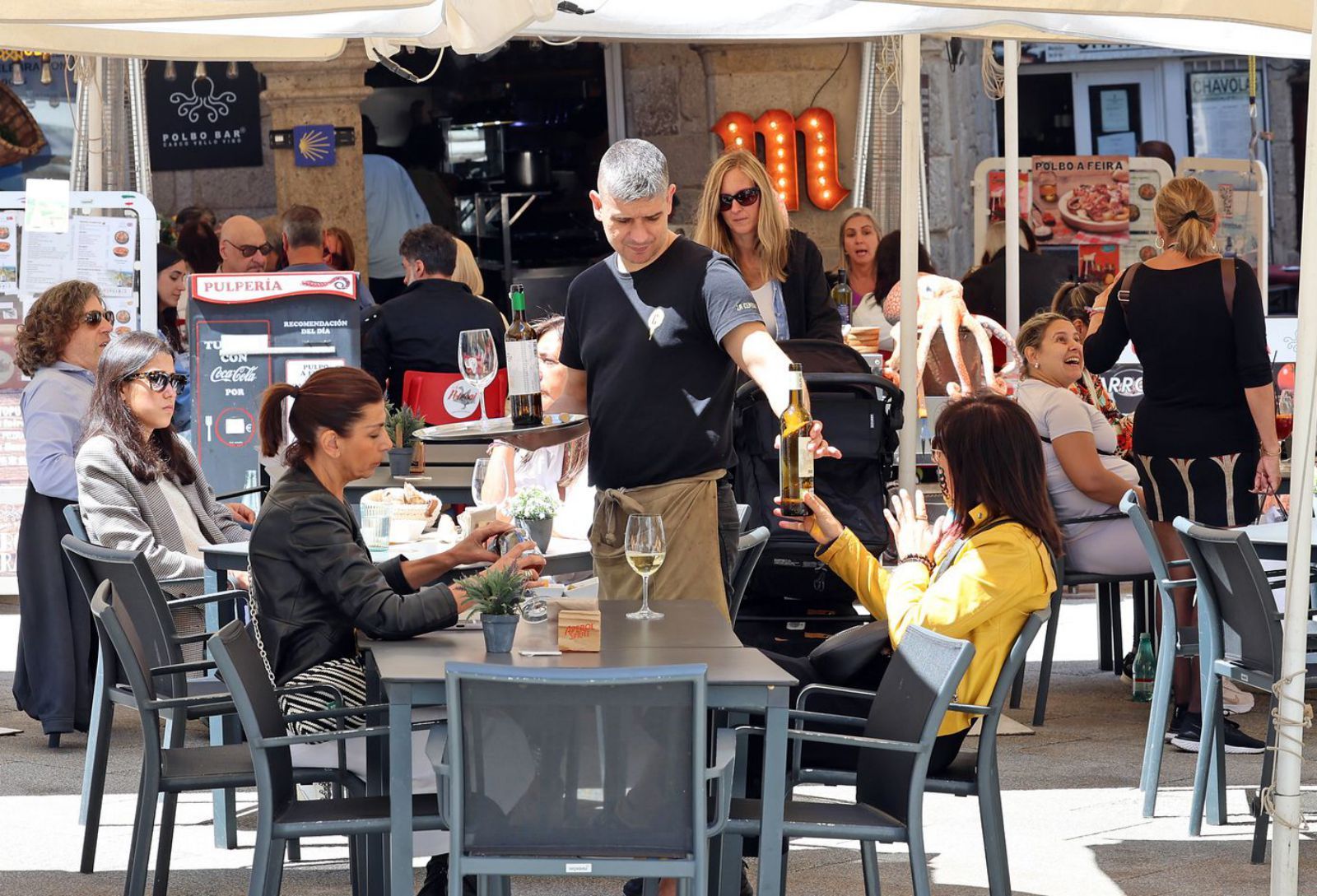 Un camarero atendiendo a las clientas de una terraza este verano en Vigo