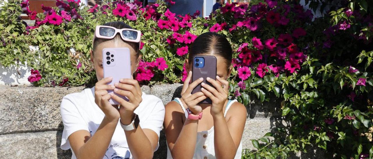 Dos niñas, mirando su teléfono móvil.