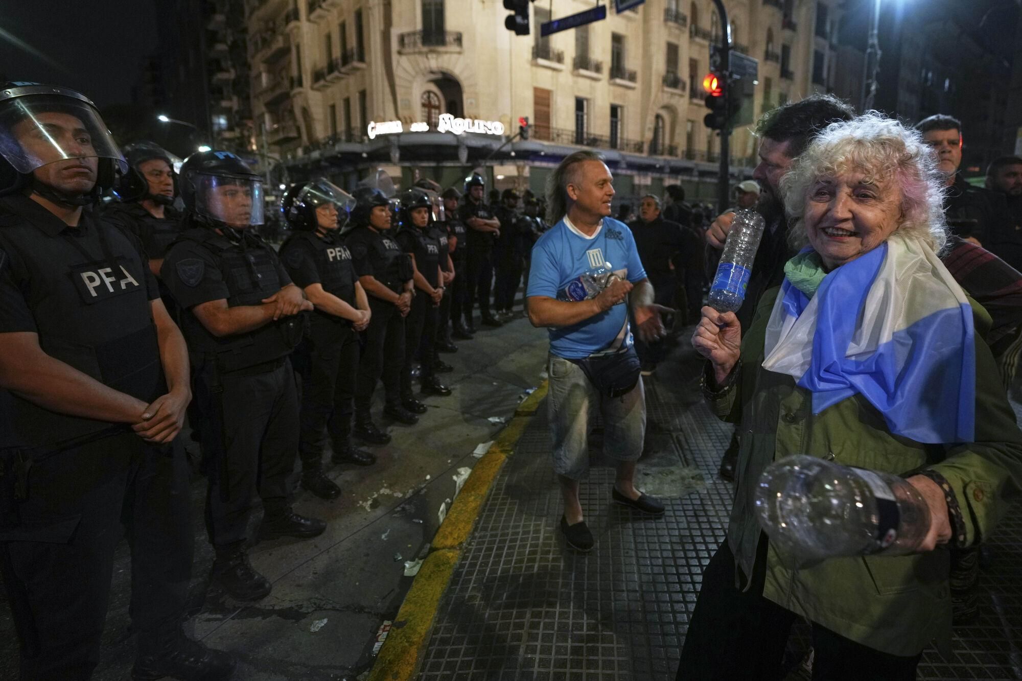 A woman bangs plastic bottles together during a protest for higher pensions and against austerity measures implemented by Javier Milei's government in Buenos Aires, Argentina, Wednesday, March 12, 2025. (AP Photo/Natacha Pisarenko)