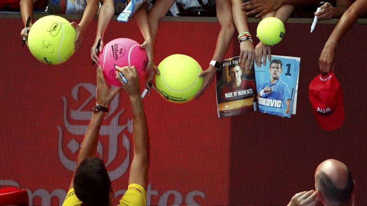 Djokovic firma autógrafos tras ganar, la pasada madrugada, al surcoreano Hyeon Chung en su debut en Australia