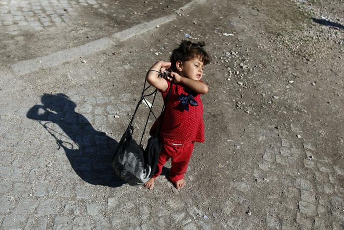 Una nena sirià intenta agafar la seva motxilla a la localitat sèrbia de Presevo.