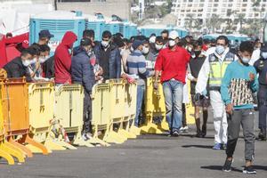 Varios inmigrantes hacen cola en el Muelle de ArguineguÃ­n, en Gran Canaria, Canarias (EspaÃ±a), a 18 de noviembre de 2020. MÃ¡s de 2.300 migrantes permanecen hacinados en este muelle tras pernoctar en el campamento que se instalÃ³ el pasado mes de agosto en el recinto portuario.