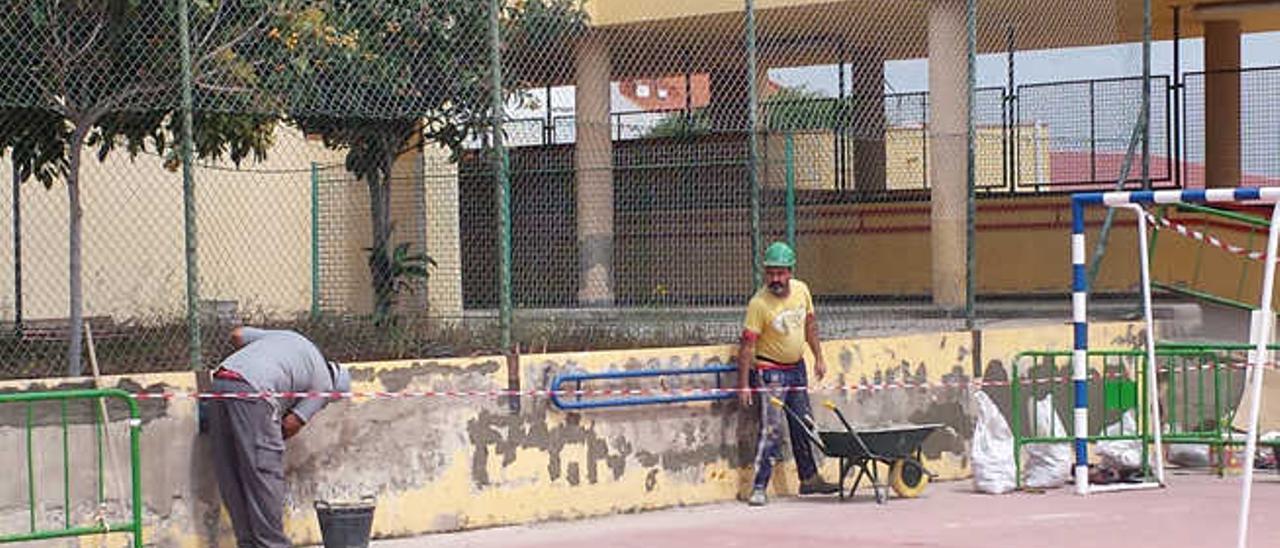Operarios realizando labores de enfoscado y pintado en un muro en el colegio público Francisco Tarajano.