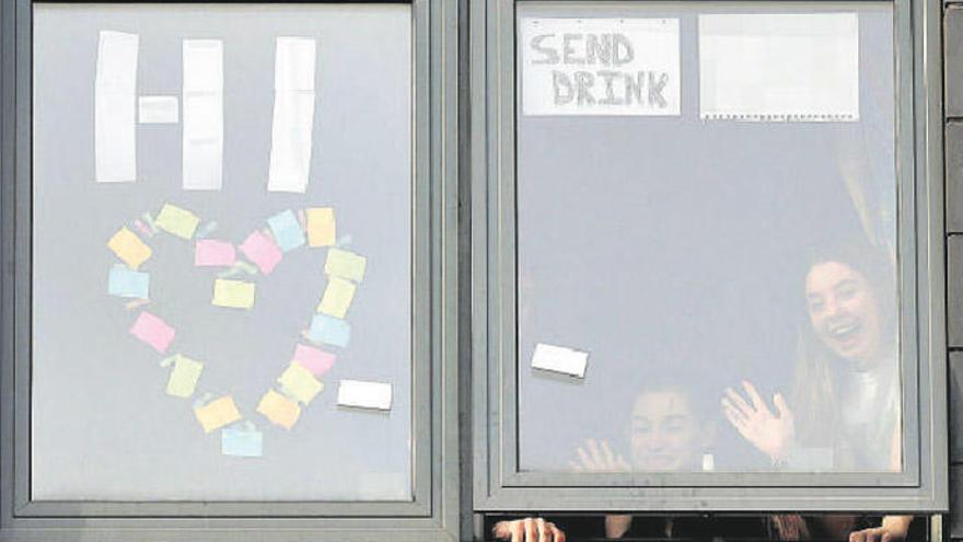 Dos estudiantes saludan desde una residencia universitaria en Sheffield, Inglaterra.